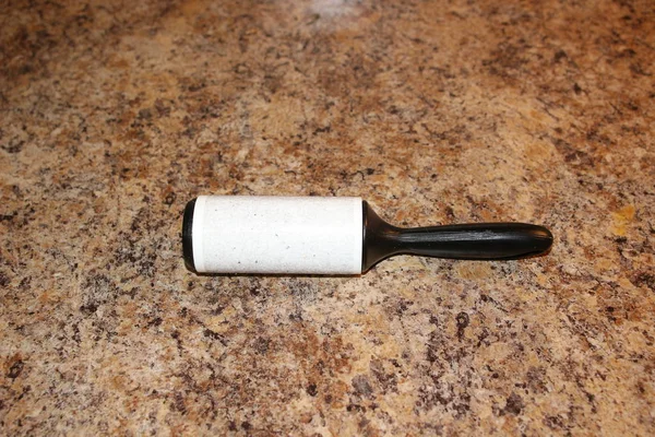Un palo de rodillo en el uso con mucho pelo y polvo en el fondo de granito, aislado — Foto de Stock