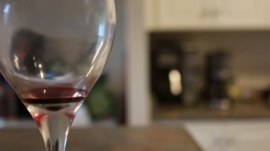 Koyu kırmızı şarap ve bulanık Restoran arka plan sahne ile ahşap counter üst çubuğunda ince kök düşük açı yakın bakış geleneksel yuvarlak kadehi şekli ile kristal berraklığında şarap kadehi kadar dolu.