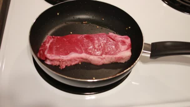 Koch braten zwei Ribeye Steaks aus nächster Nähe. Koch braten zwei Ribeye-Steaks in einer beschichteten Pfanne aus nächster Nähe — Stockvideo