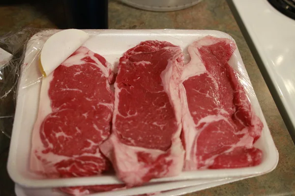 Steak de striploïne cru frais sur bois Plateau sur fond bois avec sel et poivre dans un style rustique, vue sur le dessus . — Photo