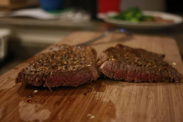 Closeup of medium rare steak with rosemary on metal table.