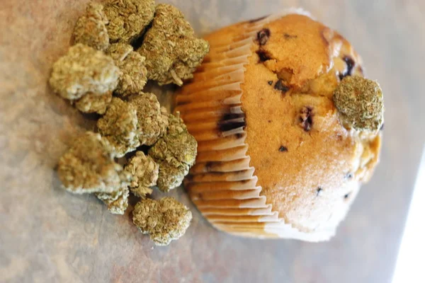 Un panecillo de cannabis junto a un montón de brotes de marihuana —  Fotos de Stock