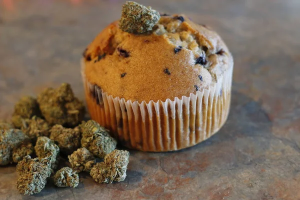 Egy kannabisz muffin egy rakás marihuána bimbó mellett. — Stock Fotó