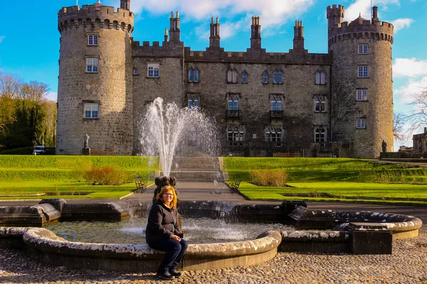 Kilkenny Ireland, 20 de febrero de 2018: foto editorial de una mujer sentada frente al castillo de kilkenny — Foto de Stock