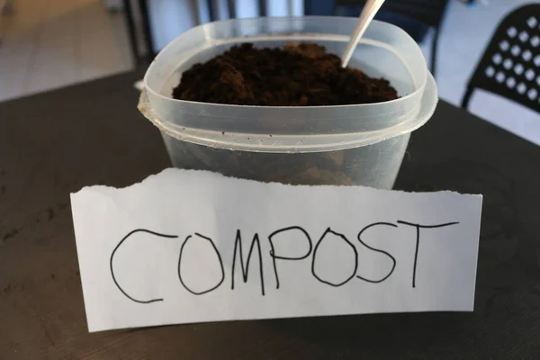 Photo of a container of used coffee grounds with a sign that says compost — Stock Photo, Image