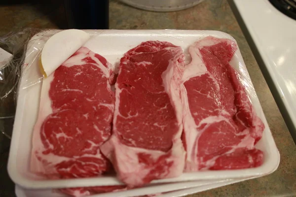 Steak de striploïne cru frais sur bois Plateau sur fond bois avec sel et poivre dans un style rustique, vue sur le dessus . — Photo