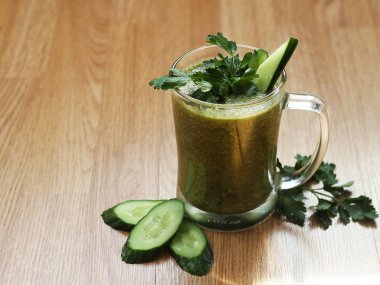 Ahşap masadaki malzemelerle harmanlanmış yeşil smoothie..