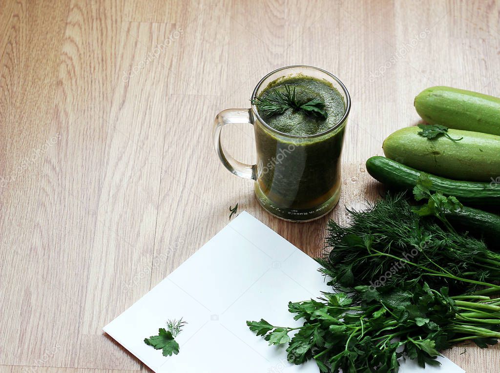 Blended green smoothie with ingredients on wooden table.
