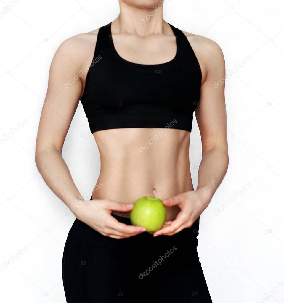 Athletic girl holding a green apple. Drinking green concept of a healthy cocktail.