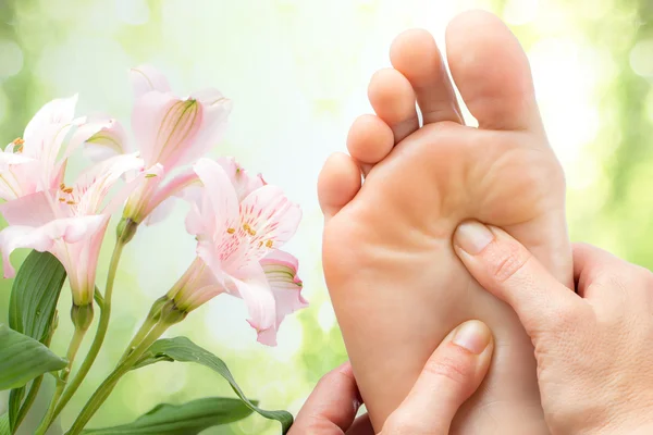 Detalhe macro de massagem nos pés ao lado de flores . — Fotografia de Stock