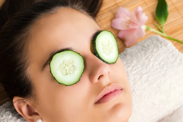 Vrouw met plakjes komkommer op ogen. — Stockfoto