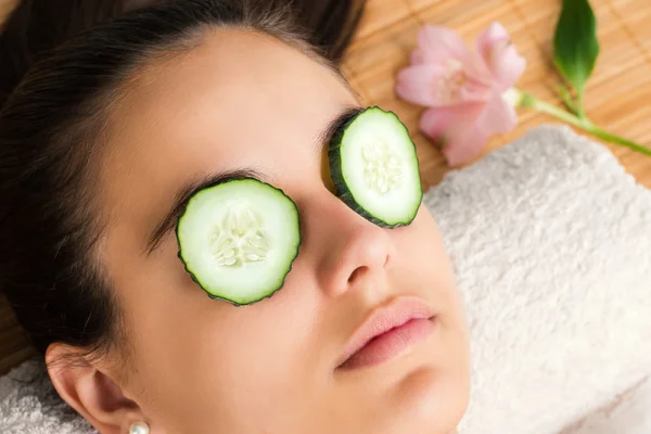 Mulher com fatias de pepino nos olhos . — Fotografia de Stock