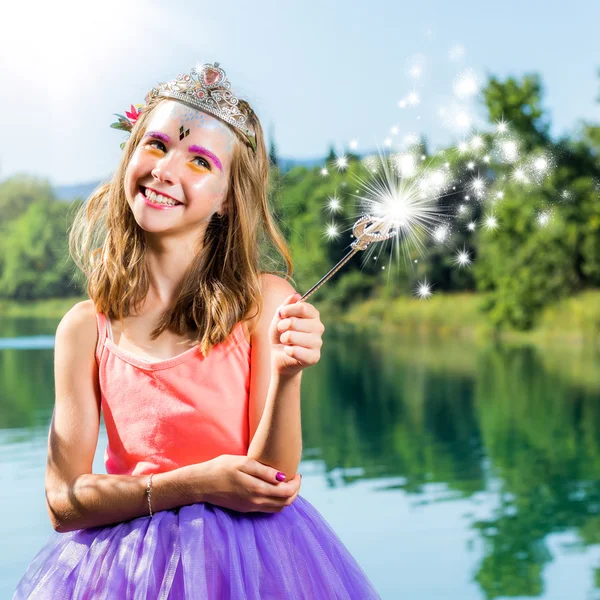 Nettes Mädchen spielt mit Zauberstab am See. — Stockfoto