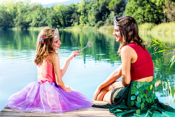 Two girls telling fairy tails at lake. — ストック写真