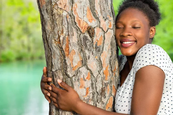 Chica africana abrazando el árbol en madera — Foto de Stock