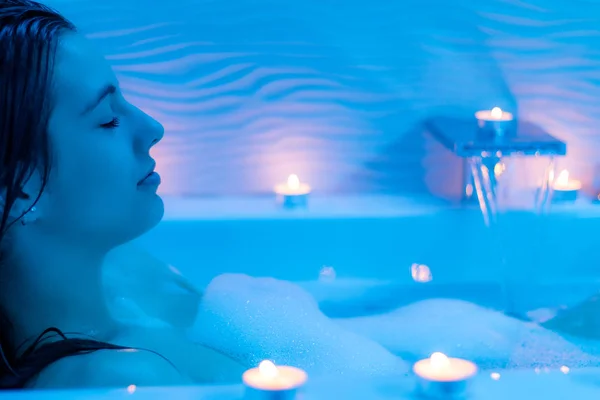 Donna in bagno di schiuma con candele — Foto Stock