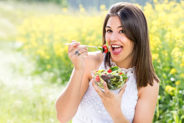 Gadis sehat yang menarik makan salad hijau di luar ruangan . — Stok Foto