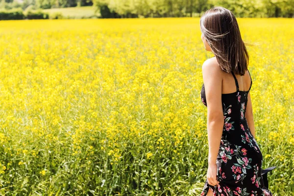 Vista trasera de la mujer junto al campo de flores amarillas . —  Fotos de Stock