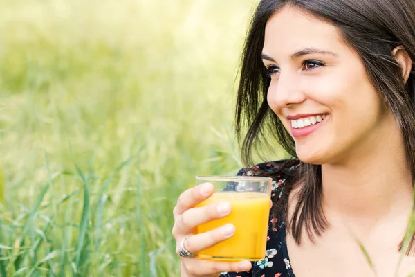 Attractive girl drinking orange juice outdoors. — Stock Photo, Image