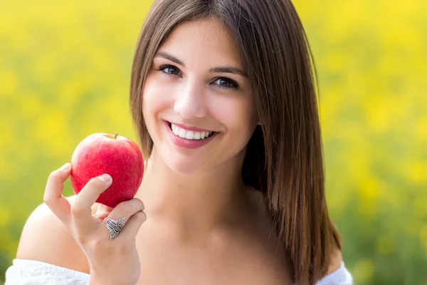 Привлекательная молодая женщина держит красное яблоко на открытом воздухе . — стоковое фото