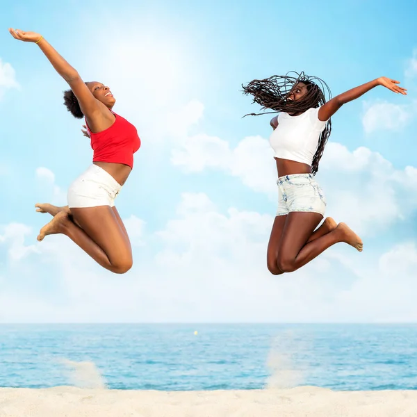 Amigos africanos pulando juntos na praia . — Fotografia de Stock