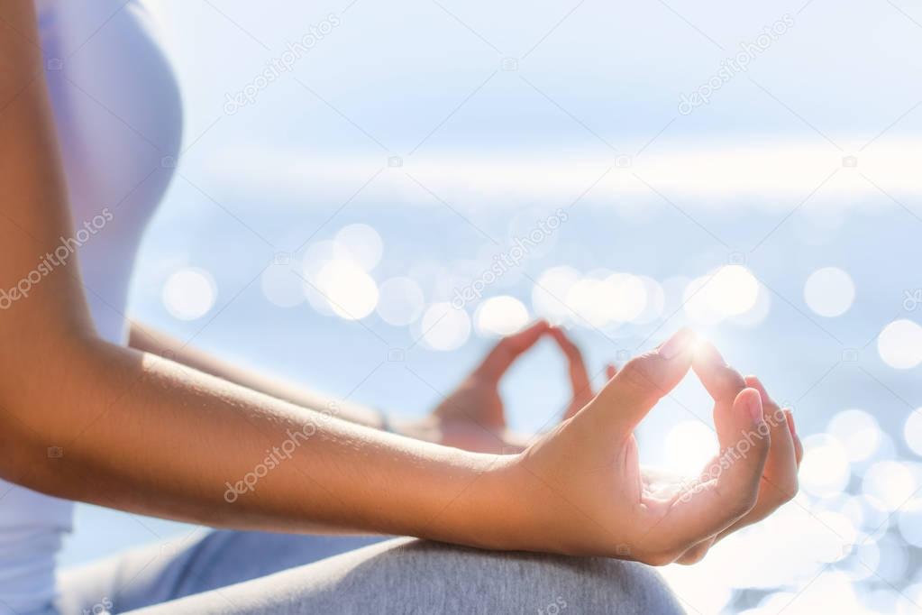 female hands in yoga position next to sea