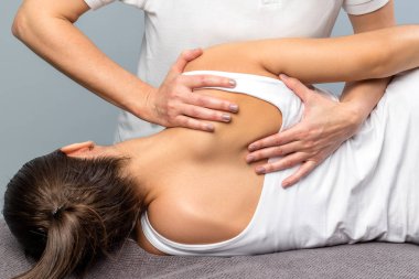 Detail of female therapist manipulating shoulder blade on patien clipart