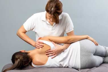 Female therapist manipulating shoulder blade on young female pat clipart