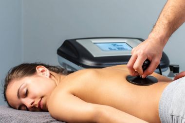 Young woman having electrotherapy session. clipart
