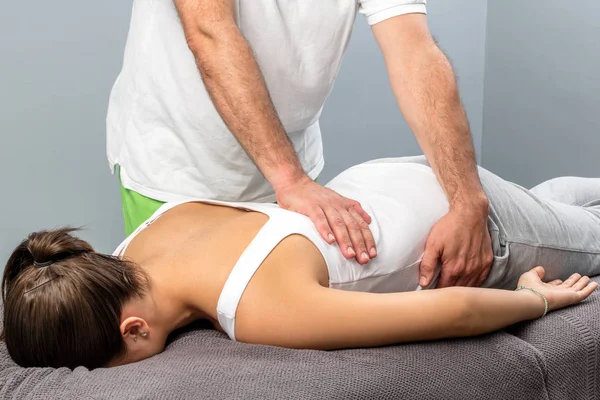 Fisioterapeuta fazendo massagem na parte inferior das costas feminina . — Fotografia de Stock