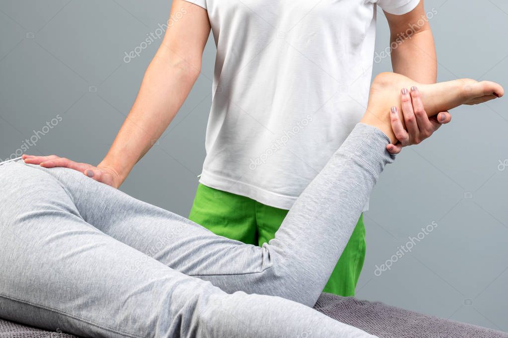 Detail of therapist manipulating female leg.