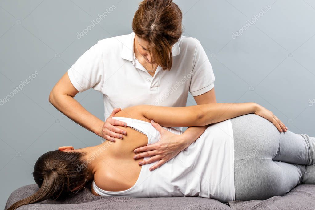 Female therapist manipulating shoulder blade on young female pat