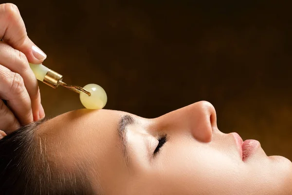 Therapeutin trägt Jade-Rolle auf der Stirn auf — Stockfoto