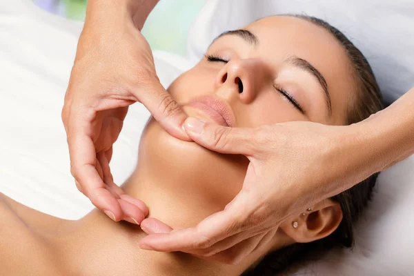 Therapeut masseren vrouwelijke kin. — Stockfoto