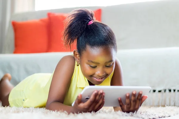 Маленька африканська дівчинка грає на планшеті у вітальні . — стокове фото