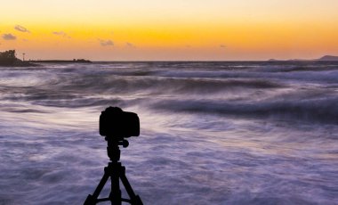 Deniz ve gün batımı arka plan ile tripod üzerinde kamera