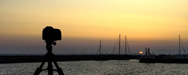 Caméra sur trépied avec mer et coucher de soleil en arrière-plan — Photo