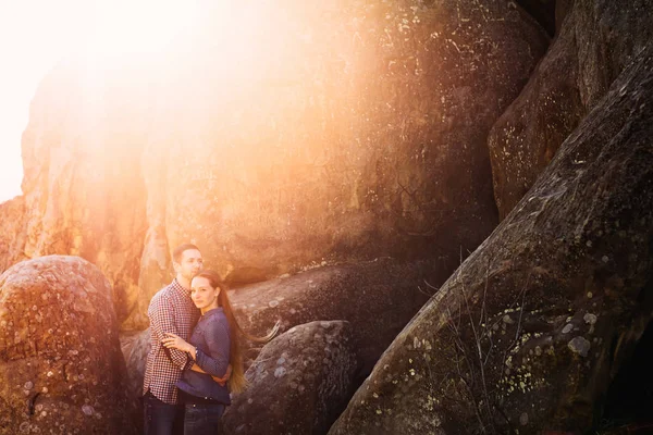 Pareja romántica abrazándose en las piedras con el sol radiante — Foto de Stock