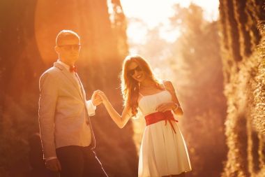 Şık çift poz ve gün batımı ışıklar içinde ağaçlar arasında dans