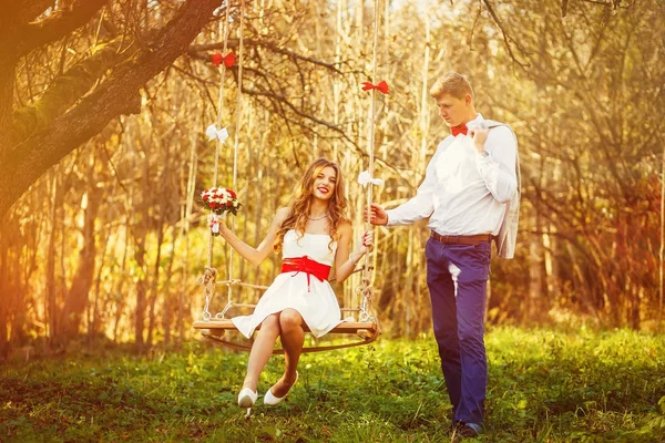 Couple heureux et sensuel se détendre sur swing dans le parc d'automne . — Photo