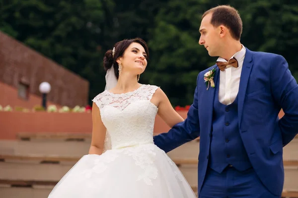 Bruidegom in blauwe pak en bruid in trouwjurk kijken naar elke ot — Stockfoto