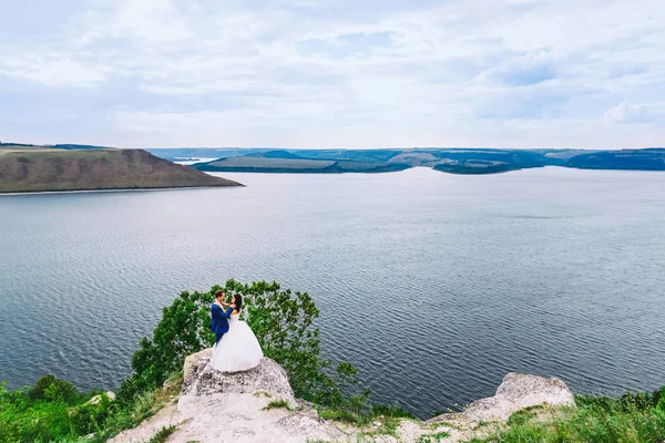 Fantastic wedding couple standing on the edge of rocky precipice