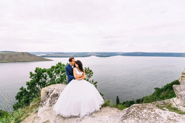 Fantastic wedding couple standing on the edge of rock above the