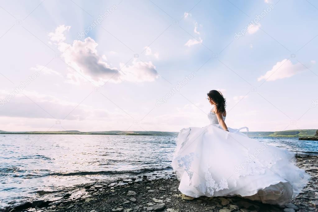 Fantastic bride in magnificent wedding dress standing on the sho