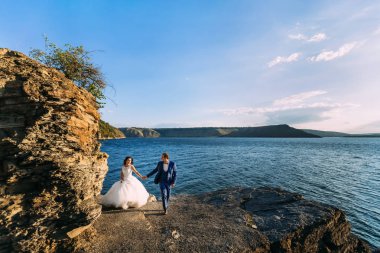 Güzel düğün çifti bir kayalık kıyısında, romantik bir yürüyüş 