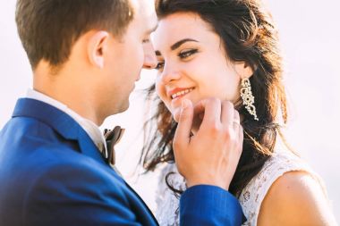 Yakışıklı damat gelinin yanaklarına hafifçe dokunarak. Kadın beyaz d