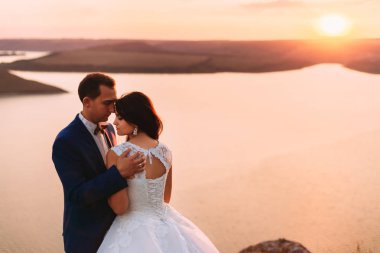 Aşağı bakıyor ve romantik günbatımı o sarılma Düğün çifti