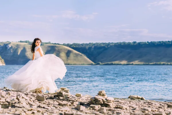 Linda noiva em vestido branco de luxo em pé na baía sorrindo — Fotografia de Stock