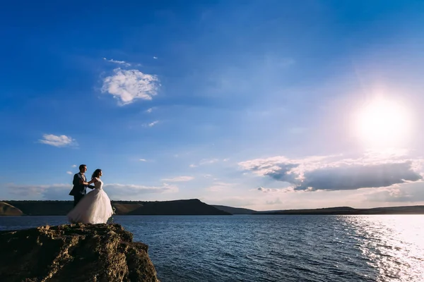 Noivo e noiva desfrutando dia ventoso no mar e de mãos dadas — Fotografia de Stock