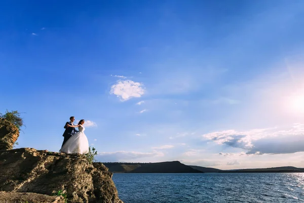 Fantástica pareja de boda abrazándose en la parte superior del borde de la roca — Foto de Stock